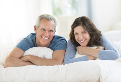 Portrait Of Happy Couple Lying Together In Bed