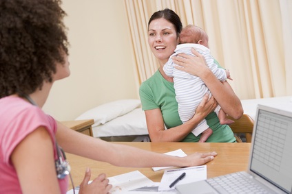 Doctor with laptop and woman in doctor's office holding baby